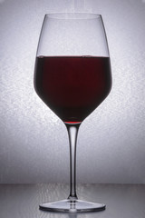 glass of wine standing on a wooden table, on bright background