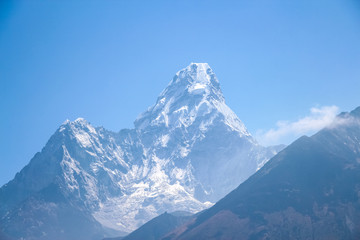 Fototapeta na wymiar View of white snowy Ama Dablam mountain peak in Himalayas during the day on the way to Everest base camp in Nepal. View from Thyanboche village. Theme of beautiful mountain landscapes.