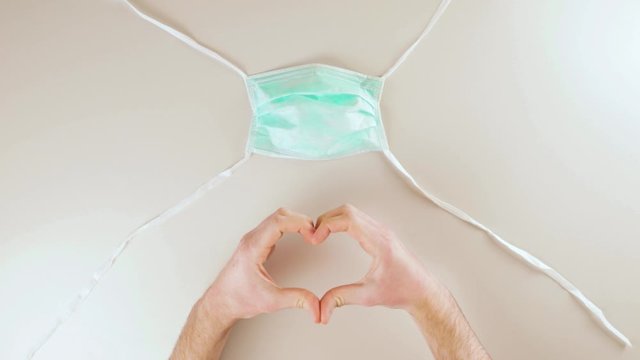 Mano che fa il simbolo del cuore con mascherina chirurgica. Ricordo vittime coronavirus covid-19
