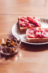 Green olives and toast with serrano ham, traditional spanish snack