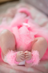 legs of a little baby girl in a pink skirt