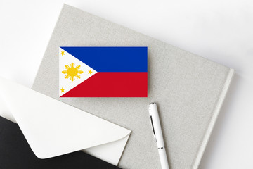 Philippines flag on minimalist letter background. National invitation envelope with white pen and notebook. Communication concept.