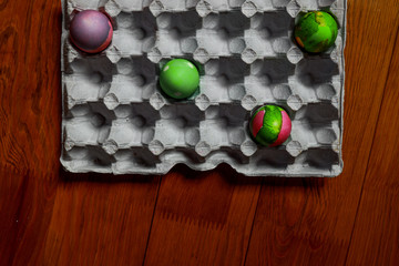 coloured easter eggs put separatelly in a tray on wooden background showing social distance,...