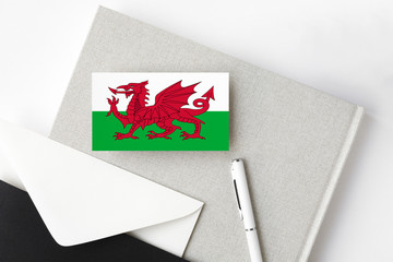 Wales flag on minimalist letter background. National invitation envelope with white pen and notebook. Communication concept.