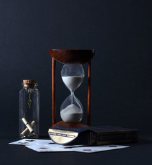 Hourglass and playing cards on a dark background