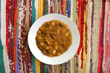 Plate of goulash on a colorful tablecloth. Top view.