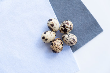 five small quail eggs lie in a circle on a blue and gray soft felt