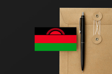 Malawi flag on craft envelope letter and black pen background. National invitation concept. Invitation for education theme.
