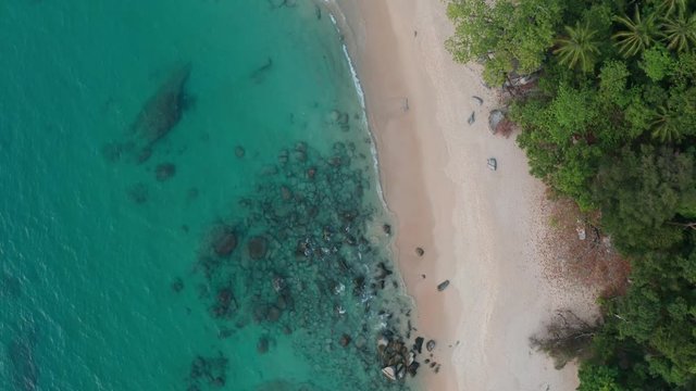 Top aerial drone view of tropical empty beach with turquoise sea water and rocks