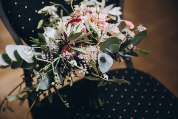 wedding bouquet of flowers and greenery with a ribbon stands on a chair