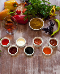 various sauces on a wooden table with fresh herbs and a glass of cognac