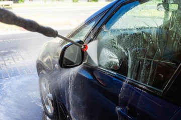 Close-up of man holding a high-pressure water sprayer for door car washing. Contactless self-service car wash. Concept disinfection and antiseptic cleaning of the vehicle, corvid-19 and coronavirus