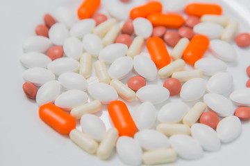 Fototapeta na wymiar Multi-colored pills in a white plate on a blue background