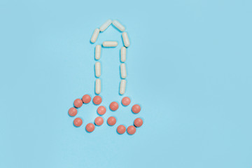 penis symbol made out of medical white tablets on a light blue background.