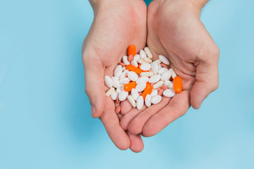 Multi-colored pills in hands on a blue background