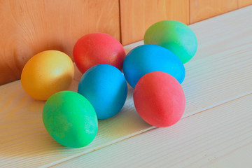 Multi-colored Easter eggs lie on a white wooden table