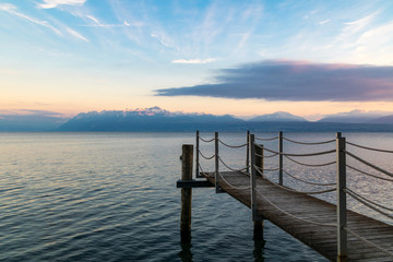 Coucher de soleil sur le Lac Léman et les montagnes des Alpes à Morges avec au premier plan un ponton (Suisse)