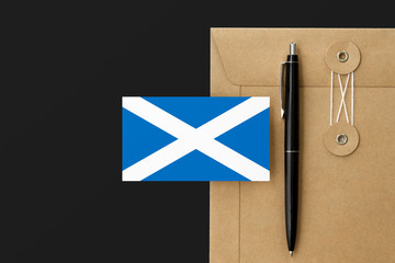 Scotland flag on craft envelope letter and black pen background. National invitation concept. Invitation for education theme.