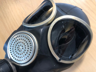 Naklejka premium Black rubber gas mask on a wood background. Industrial safety, dust protection respirator, breathing respiratory mask