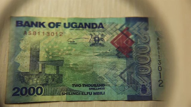 View a Two thousand Ugandan shillings bill lying on a table with a magnifying glass. concept of business and finance. reverse side