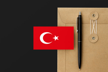 Turkey flag on craft envelope letter and black pen background. National invitation concept....
