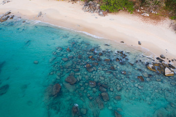 Aerial drone view of tropical empty beach with turquoise sea water and rocks