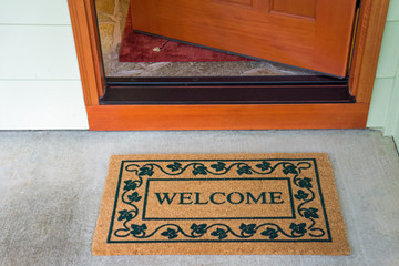 Recently delivered packages sit on a welcome mat in front of a wooden door to a residence.