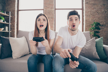 Obraz premium Portrait of her she his he attractive focused concentrated worried friends friendship sitting on divan playing online game having fun at modern industrial loft style brick interior house