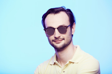 Studio shot of handsome man wearing sunglasses over blue background