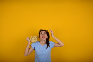 surprised woman with popcorn looks up at copy space