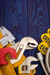 Plumbing tools in the yellow bag and spare parts on blue wooden boards are used to replace or repair