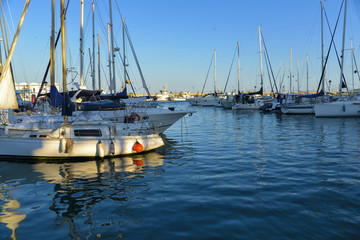 Fototapeta premium White yachts and boats moored in golden sunrise in marina of Estepona, Spain.