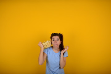 woman with popcorn in a blue t-shirt on a yellow background