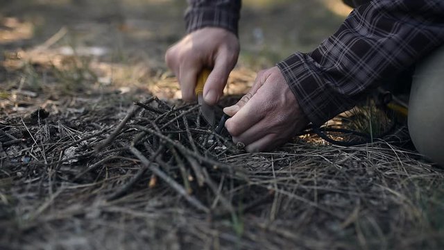 Starting campfire with flint, knife and tinder, close up