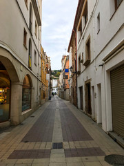 Fototapeta na wymiar Staight spanish street with modern stone pavement and storehouses