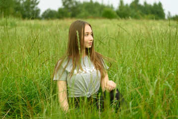 Fototapeta premium Girl sitting in the grass in the meadow