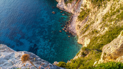 Blue and turqoise water in a bay, from top view, rocks and green shrubs in the deep