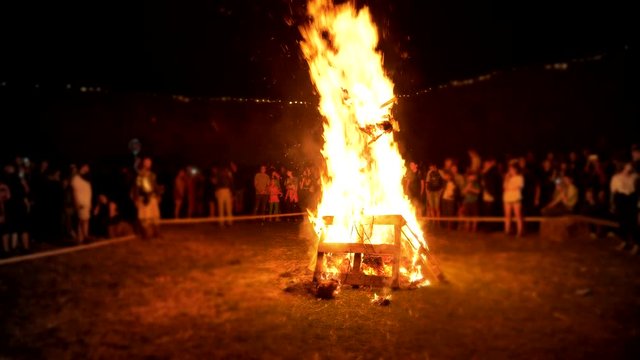 Silhouettes of people around big ritual bonfire.