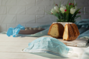 Medical blue protective disposable mask on a background of Easter baking. Protection against viruses. The concept of the celebration of Holy Easter in the context of the coronavirus pandemic.