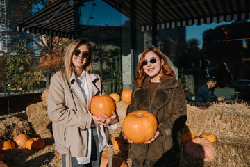 Girls holds pumpkins in hands. Outdoor photo.