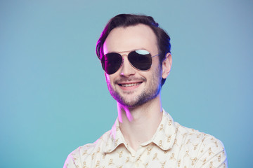 Studio shot of handsome man wearing sunglasses over green background.