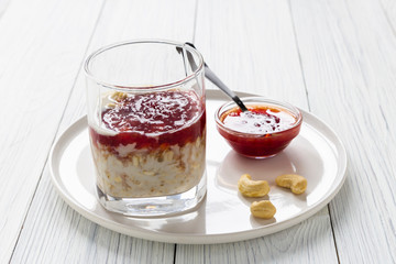 Oatmeal with milk and strawberry jam in glass on white wooden table. healthy organic food. breakfast