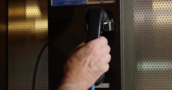 Older man picks up payphone telephone and deposits money - close up