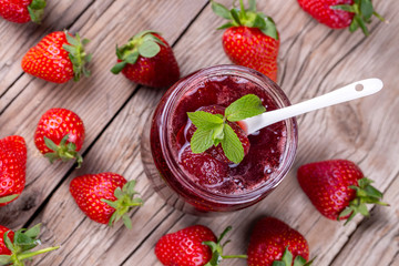 Homemade delicious strawberry jam and strawberry on a rustic wooden table