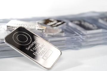 Minted silver bars weighing one troy ounce unpacked and in plastic packaging. Selective focus.