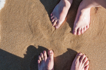 Couple feet on wet sand on the beach