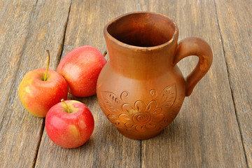 Obraz na płótnie Canvas Apples and crock with cider on a wooden table.