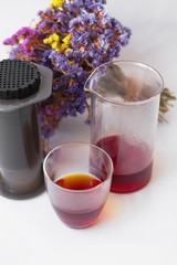 White background, strong, morning, specialty coffee brewed by an alternative method from gadget. Bouquet of field flowers and glassware.