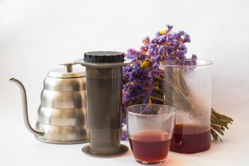 White background, strong, morning, specialty coffee brewed by an alternative method from gadget. Bouquet of field flowers and glassware.