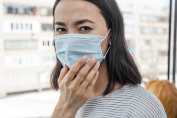 Portrait of a young Asian woman in a medical mask close-up on the street. protection from...